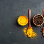 زردچوبه و فلفل سیاه در کاسه و قاشق چوبی