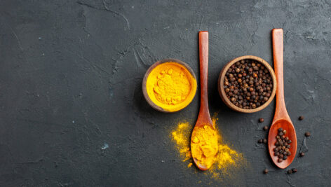 زردچوبه و فلفل سیاه در کاسه و قاشق چوبی