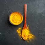 زردچوبه و فلفل سیاه در کاسه و قاشق چوبی