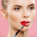 دختر جوان در حال زدن رژ لب قرمز