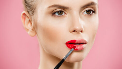 دختر جوان در حال زدن رژ لب قرمز