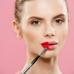 دختر جوان در حال زدن رژ لب قرمز