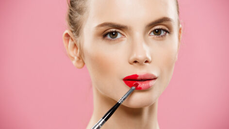 دختر جوان در حال زدن رژ لب قرمز