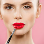 دختر جوان در حال زدن رژ لب قرمز