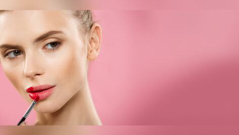 دختر جوان در حال زدن رژ لب قرمز