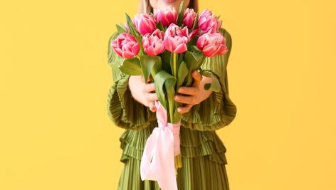 دختر جوان با دسته گل لاله صورتی